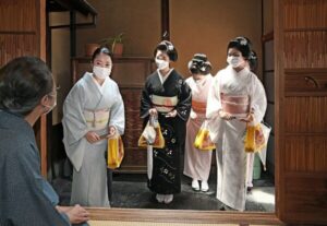 The photo shows maiko wearing masks to make Hassaku greetings